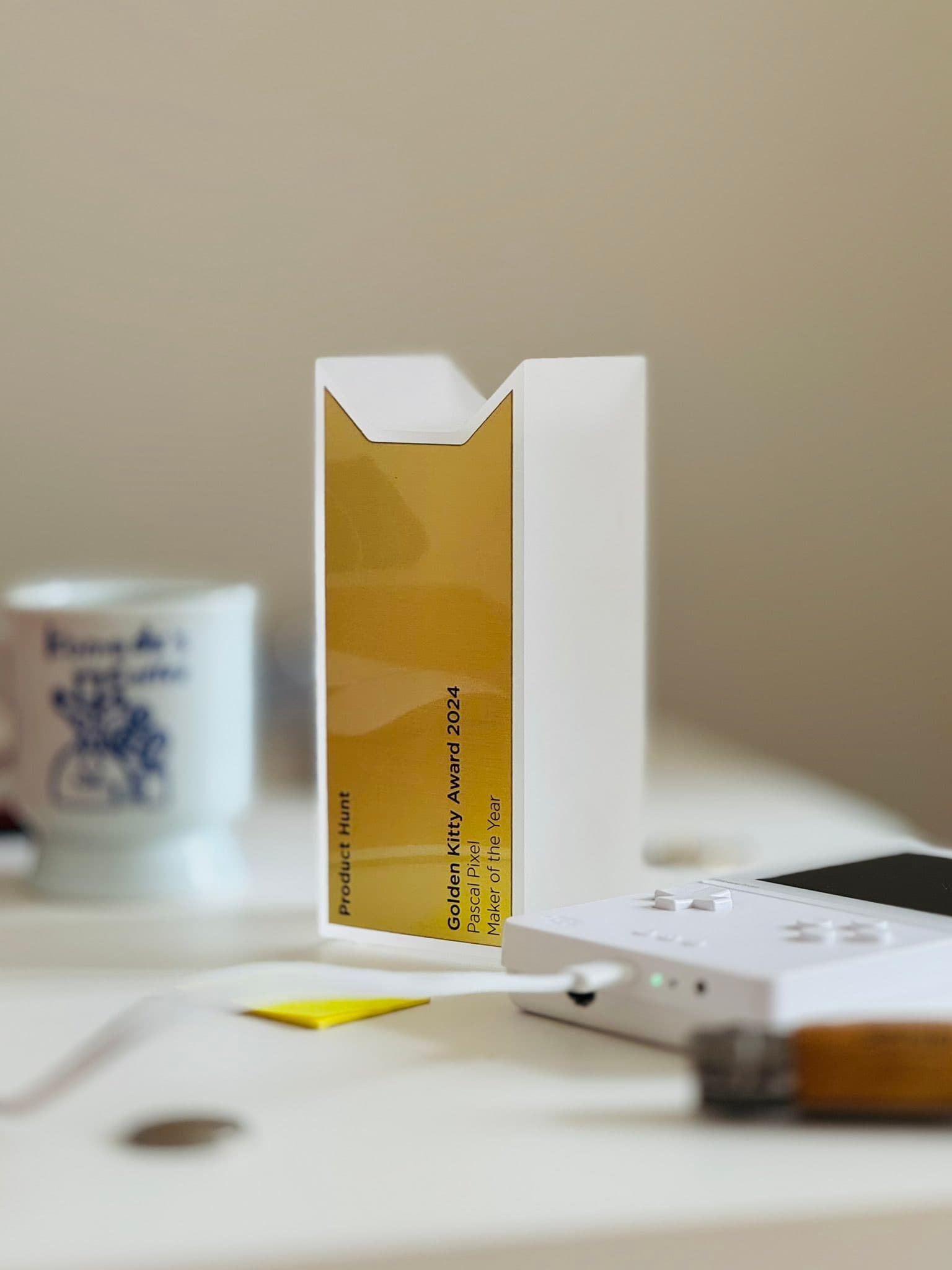 Product Hunt Maker of the Year Golden Kitty Award standing on a desk next to a gameboy and coffee cup